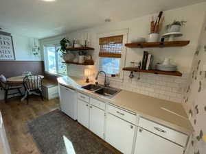 Kitchen featuring wood finished floors, open shelves, a sink, wainscoting, and dishwasher
