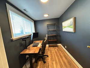 Office space featuring visible vents, wood finished floors, and baseboards