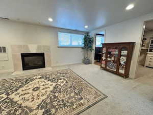 Carpeted living room with recessed lighting, baseboards, and a tiled fireplace