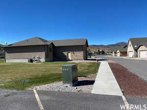 Exterior space featuring a lawn, a mountain view, and stucco siding