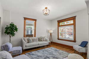 Living area with beautiful stained-glass window, original wood window casings, new light fixture, and hardwood floors.