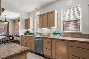 Kitchen with newer stainless steel dishwasher, new pendant light, and lots of natural light.