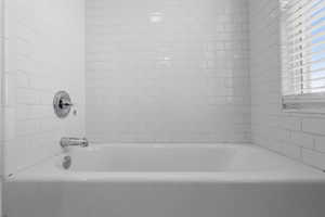 Upstairs light-filled bathroom with beautiful windows and white-tiled bathtub.