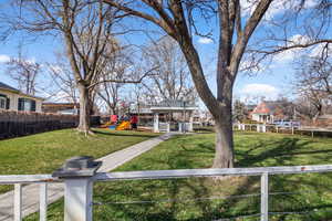 View of Westminster Park just steps from the home. Features a gazebo, playground equipment, swings, and mature trees.