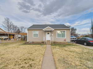 Bungalow with a front lawn, fence, and roof with shingles