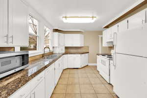 Kitchen with white appliances, light tile patterned flooring, a sink, tile counters, and under cabinet range hood