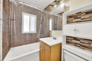 Full bathroom featuring toilet, vanity, and shower / tub combo with curtain