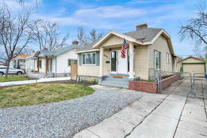 Bungalow-style home with a chimney, a garage, an outbuilding, driveway, and a gate