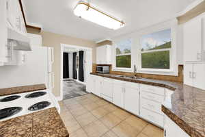 Kitchen with tile countertops, white cabinetry, a sink, dishwasher, and stainless steel microwave