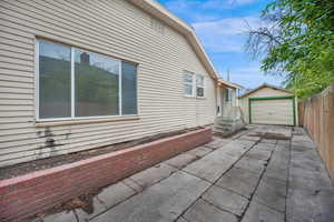 View of side of property featuring a detached garage, an outbuilding, driveway, and fence