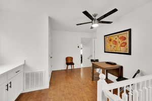 Hall with light wood finished floors, visible vents, and baseboards