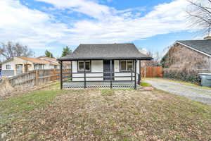 Bungalow-style house featuring fence, gravel driveway, a front yard, and a shingled roof