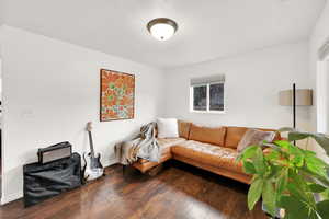 Living room with dark wood-type flooring, baseboards, and a textured ceiling