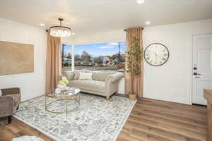 Living room with recessed lighting, baseboards, a notable chandelier, and wood finished floors