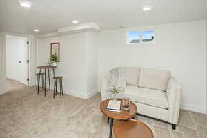 Living area with visible vents, baseboards, a textured ceiling, and carpet flooring