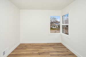 Spare room with visible vents, baseboards, and wood finished floors