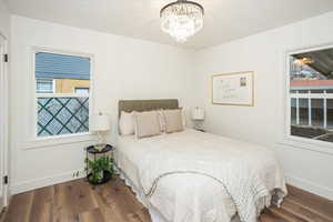 Bedroom with multiple windows, an inviting chandelier, and wood finished floors