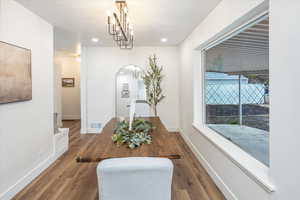 Dining space with baseboards, wood finished floors, visible vents, and a chandelier