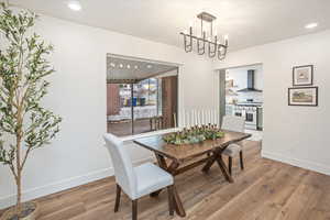 Dining area with recessed lighting, a notable chandelier, wood finished floors, and baseboards