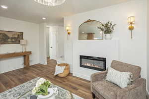 Living room with a glass covered fireplace, recessed lighting, wood finished floors, and baseboards