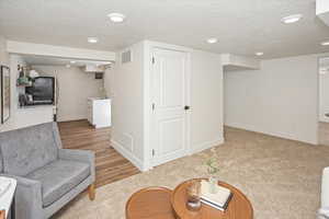 Living area with visible vents, a textured ceiling, and baseboards