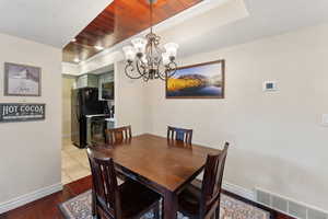 Dining room with visible vents, baseboards, wooden ceiling, an inviting chandelier, and wood finished floors