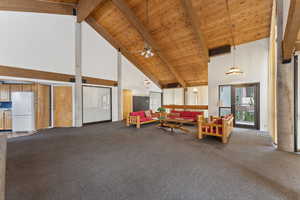 Living room with beamed ceiling, wood ceiling, a ceiling fan, and carpet floors