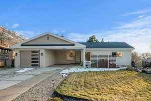 View of front of property featuring an attached carport, concrete driveway, brick siding, and a front yard