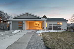 Contemporary house with brick siding, fence, a front yard, a garage, and driveway