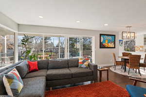 Living area featuring dark wood finished floors, a notable chandelier, recessed lighting, and baseboards