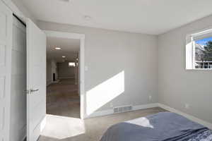 Carpeted bedroom with a fireplace, visible vents, and baseboards