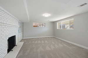 Unfurnished living room with a wealth of natural light, visible vents, carpet flooring, and baseboards