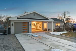 Contemporary house with a garage, brick siding, driveway, and fence