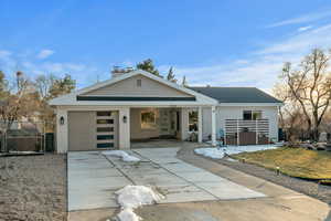 View of front of home featuring brick siding, an attached garage, driveway, and fence