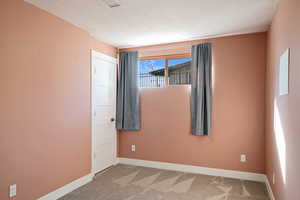 Carpeted empty room featuring baseboards and a textured ceiling