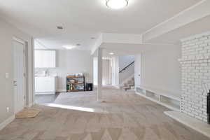 Finished below grade area with visible vents, a brick fireplace, stairs, and carpet