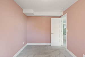 Carpeted empty room with a textured ceiling and baseboards