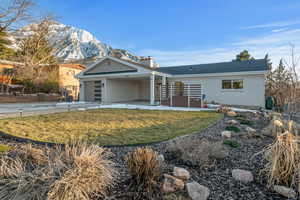 Front of house featuring driveway, a yard, brick siding, a chimney, and a mountain view