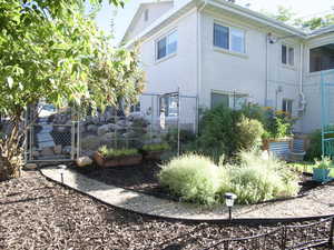 View of property exterior with a garden, a gate, and fence in the fall