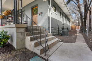 View of side of home with brick siding, central air condition unit, and fence