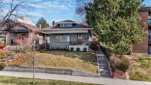 Bungalow featuring a front yard, covered porch, and a chimney