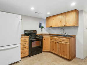 Kitchen featuring black gas range, freestanding refrigerator, and recessed lighting