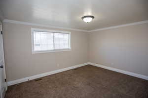 Bedroom featuring new paint, baseboards, dark carpet, and ornamental molding