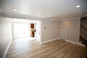 Family room featuring new LVP flooring, ornamental molding, and stairs