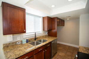 Kitchen featuring a sink, a tray ceiling, stainless steel dishwasher, and ornamental molding