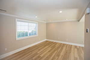 Family room with new LVP flooring, crown molding, baseboards, and recessed lighting