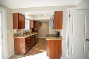 Kitchen featuring appliances with stainless steel finishes, light granite countertops, a tray ceiling, and a sink