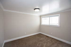 Bedroom with crown molding, new paint, baseboards, visible vents, and dark carpet