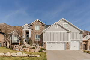 Craftsman-style home featuring stone siding, board and batten siding, concrete driveway, and a garage