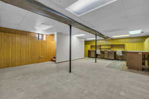 Basement featuring stairway, wooden walls, and carpet flooring